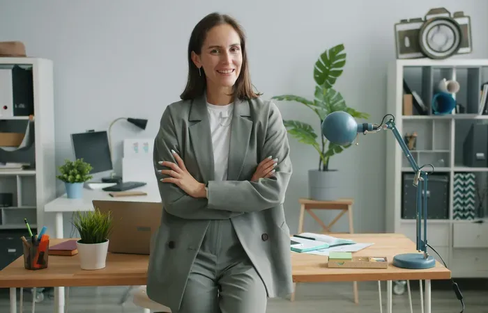 Smiling entrepreneur in a modern workspace with laptop and plants, showing a local business on City Directory 360